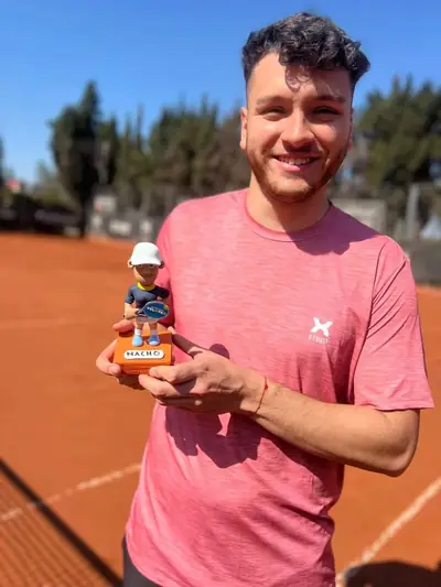 El primer campeón de un torneo PELOTEO, sonriendo con su trofeo en la cancha.